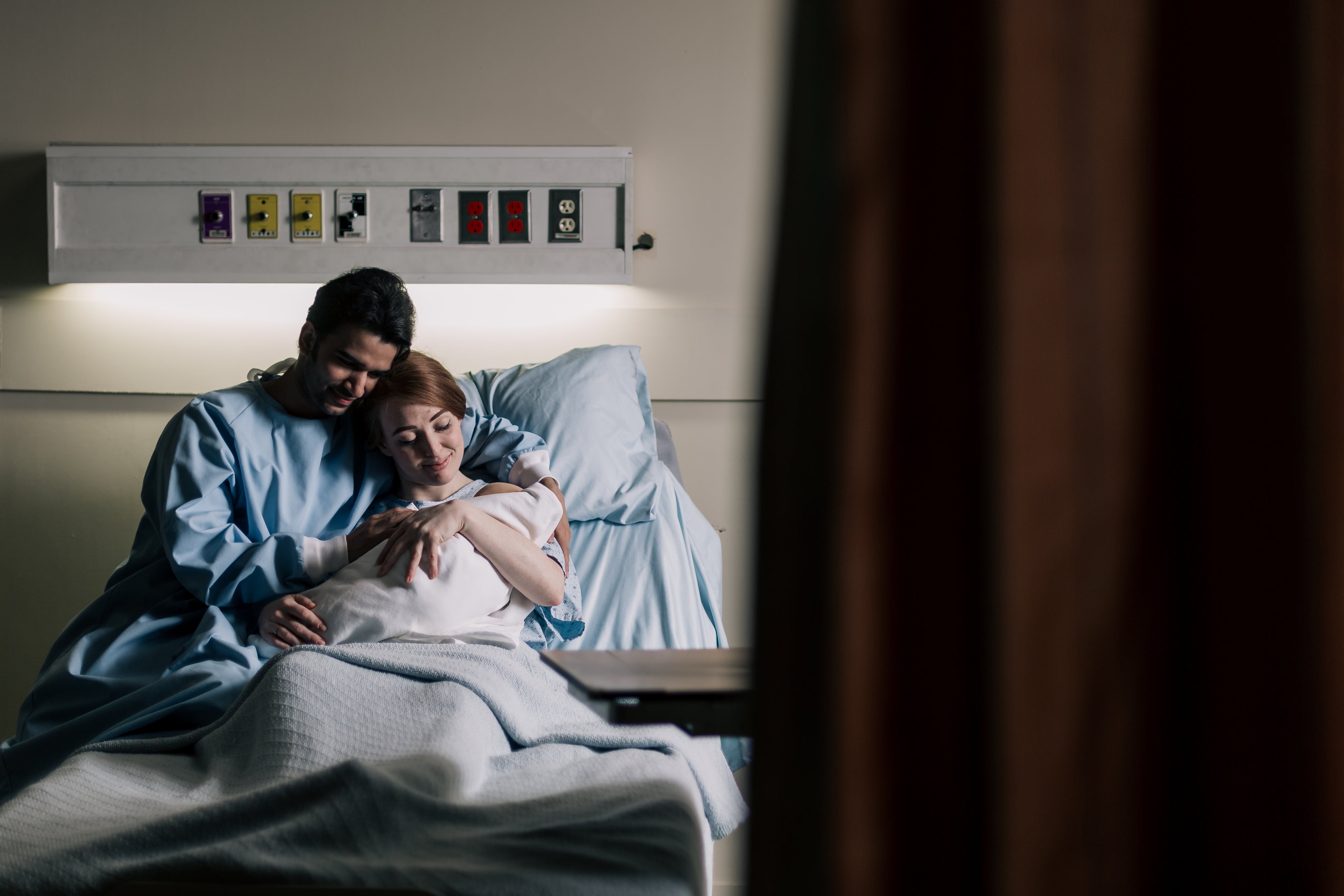 mother-and-father-embrace-in-hospital-bed-while-admiring-baby.jpg