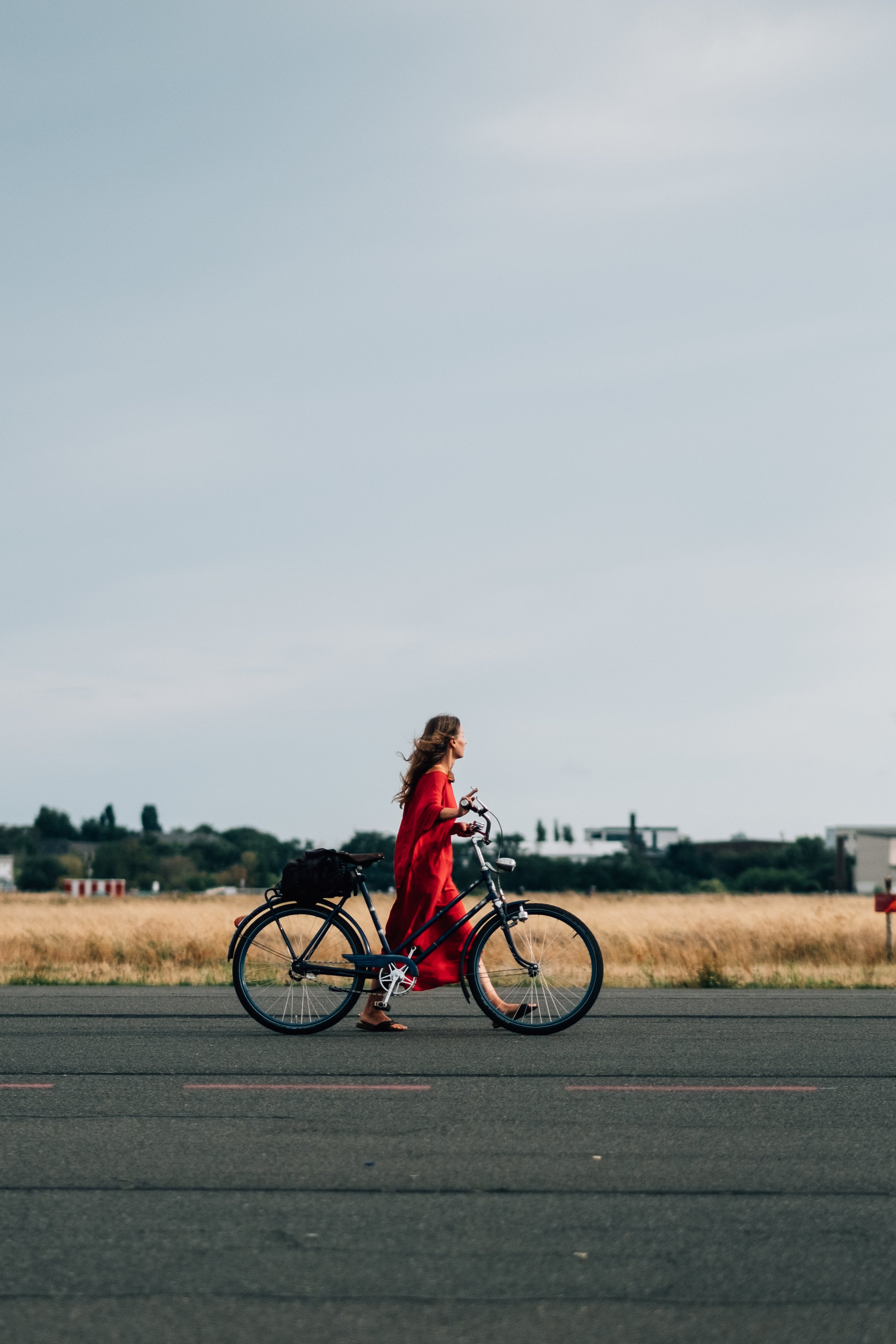 person-in-red-dress-walks-bicycle-down-the-road.jpg